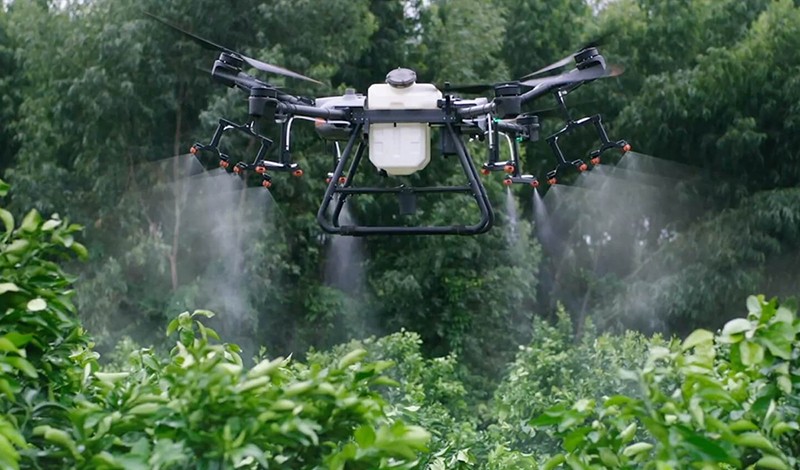 Dron agrícola aplicando sobre huerto frutal